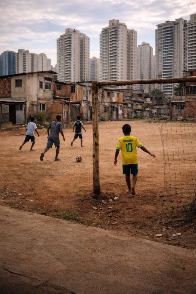 Crianças jogando futebol de rua com a camisa da Seleção.